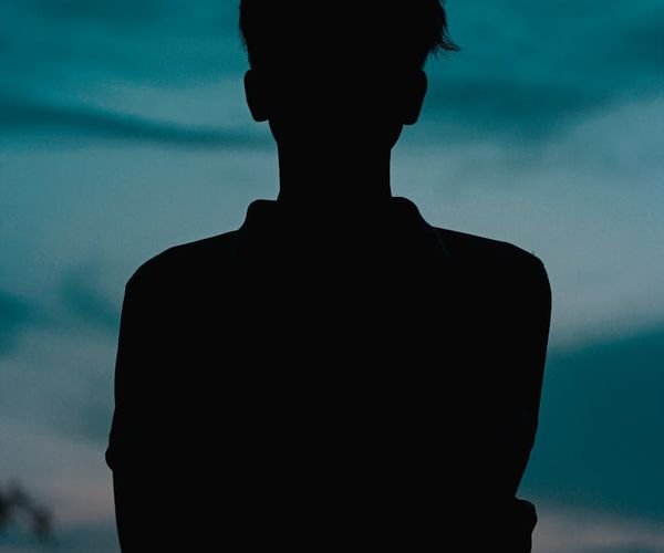 Person meditating peacefully, silhouetted against a golden-hued background.